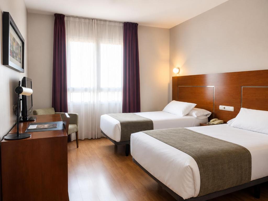 a hotel room with two beds and a desk at Hotel Andia in Orcoyen