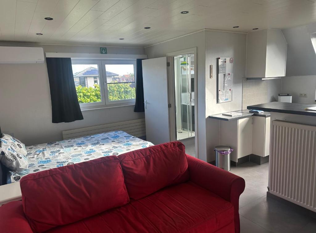 a living room with a red couch and a bed at de Zeester in Bredene-aan-Zee