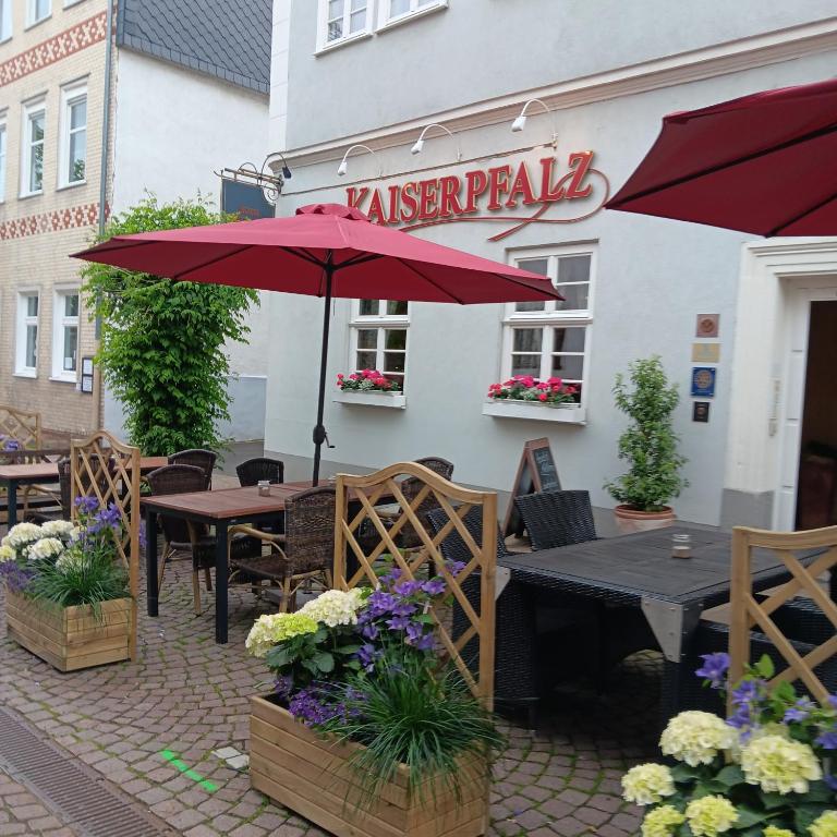 a patio with tables and umbrellas in front of a restaurant at Hotel Kaiserpfalz in Fritzlar