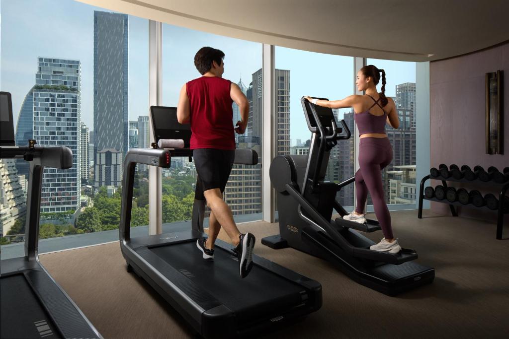 A bright high-floor gym with cardio equipment and city views.