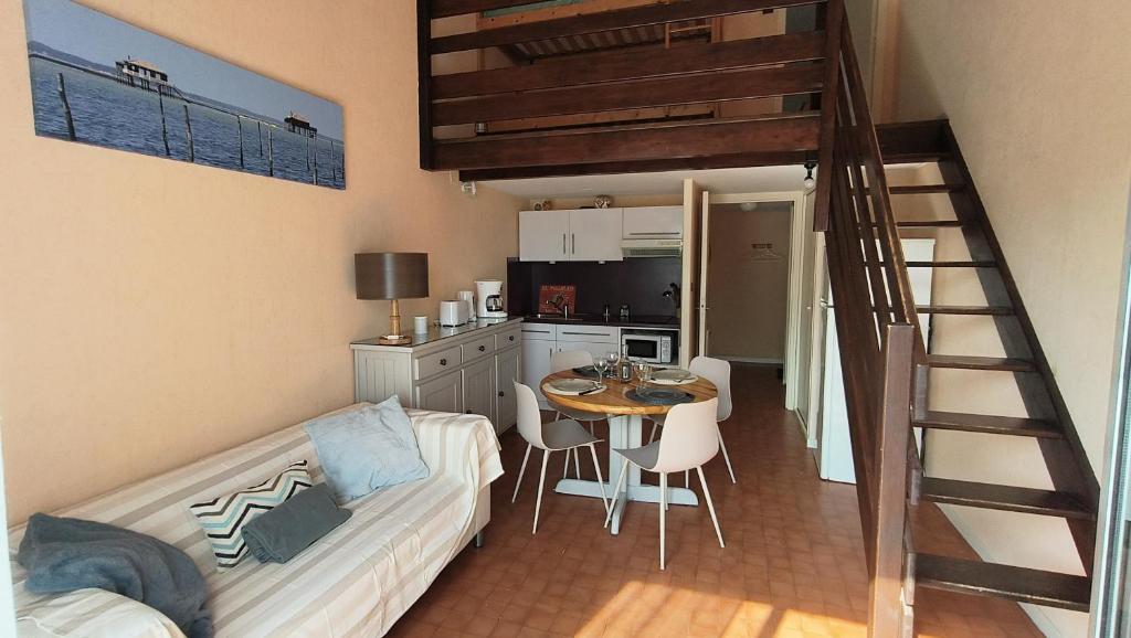 a living room with a couch and a table and a kitchen at Appartement du Port Neuf in Lanton