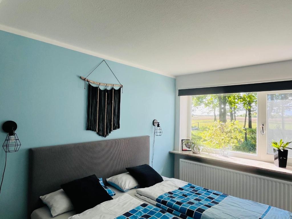 a bedroom with a bed with blue walls and a window at Fewo Sort Sol - Auszeit in perfekter Alleinlage in Aventoft