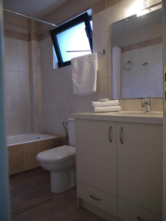 a bathroom with a toilet and a sink and a mirror at Portela Apartments Kampoula in Keratokampos