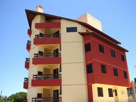 un edificio de apartamentos rojo y blanco con techo rojo en Apartamento Village Santinho en Florianópolis
