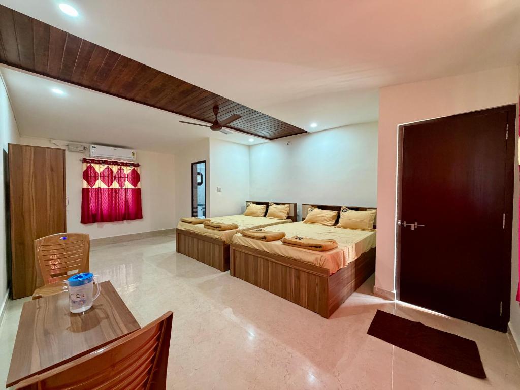 a bedroom with two beds and a table in it at AR Cottage in Udupi