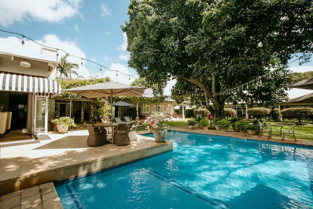 a swimming pool with a table and an umbrella at Highlands House in Harare
