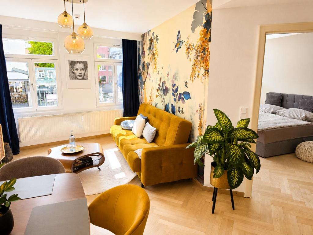 a living room with a yellow couch and a bed at Modernes Apartment im Herzen der Ravensburger Altstadt in Ravensburg