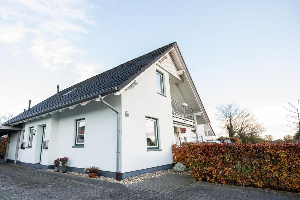 a white house with a black roof at Ferienwohnung Auszeit mit Waldgeflüster 35231 in Hesel
