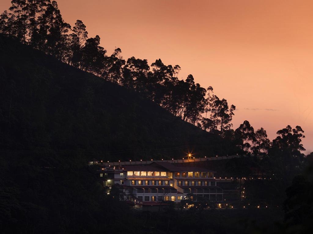 a building on the side of a hill at night at Abad Copper Castle Resort in Munnar