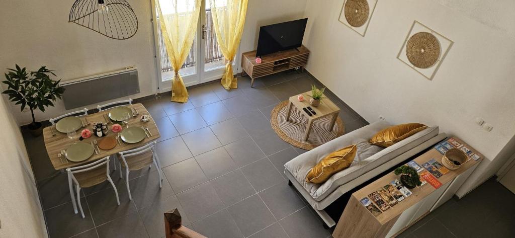 an overhead view of a living room with a couch and a table at Appartement près des Grands Buffets climatisé in Narbonne