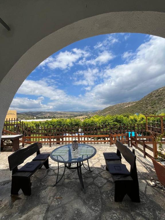 a patio with a table and chairs and a view of a vineyard at The Citrus Valley in Pissouri