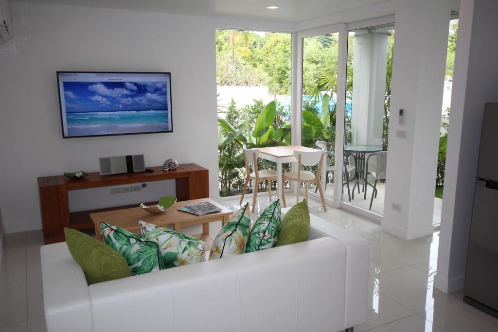 a living room with a white couch with pillows at Samui Sunrise 41B in Choeng Mon Beach