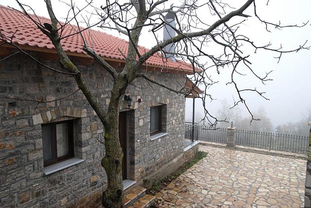 um edifício de pedra com uma árvore em frente em Oreini Nafpaktia Houses em Palaiópirgos