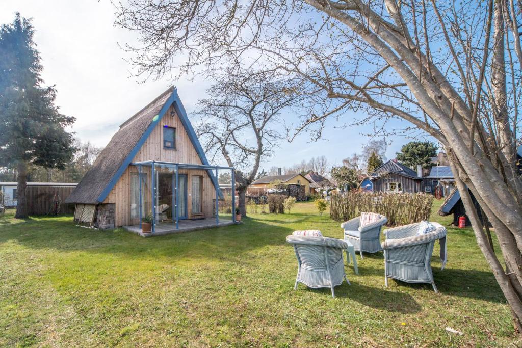 a house with a thatched roof and chairs in the yard at Hexenhaus Finn - Nichtraucher Grundstück in Bodstedt