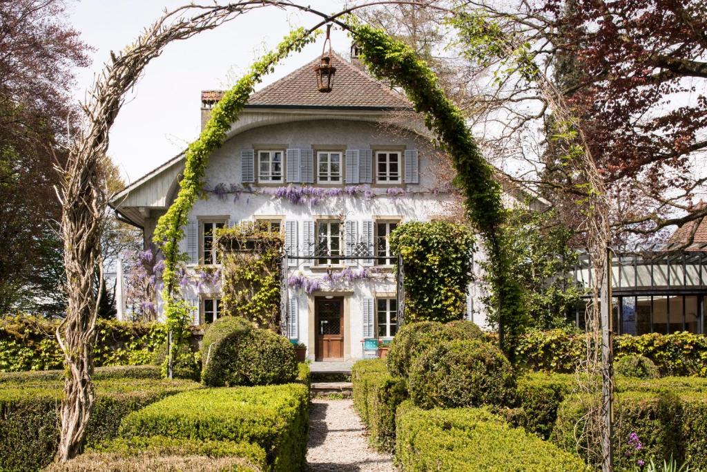 a house covered in ivy with a garden at Auberge aux 4 Vents in Fribourg