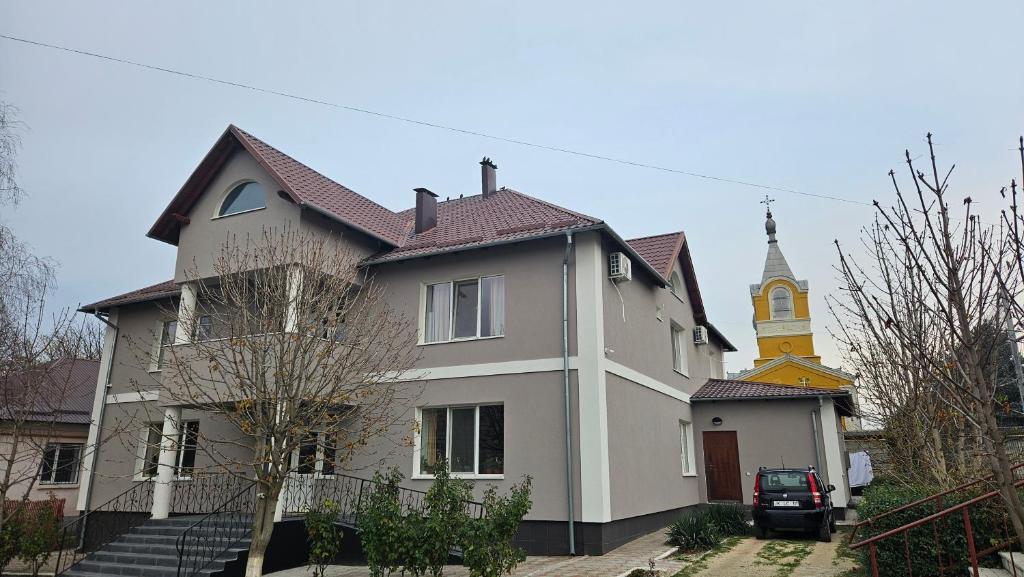 a large white house with a church in the background at Casa Regina Pacis in Vărvăreuca