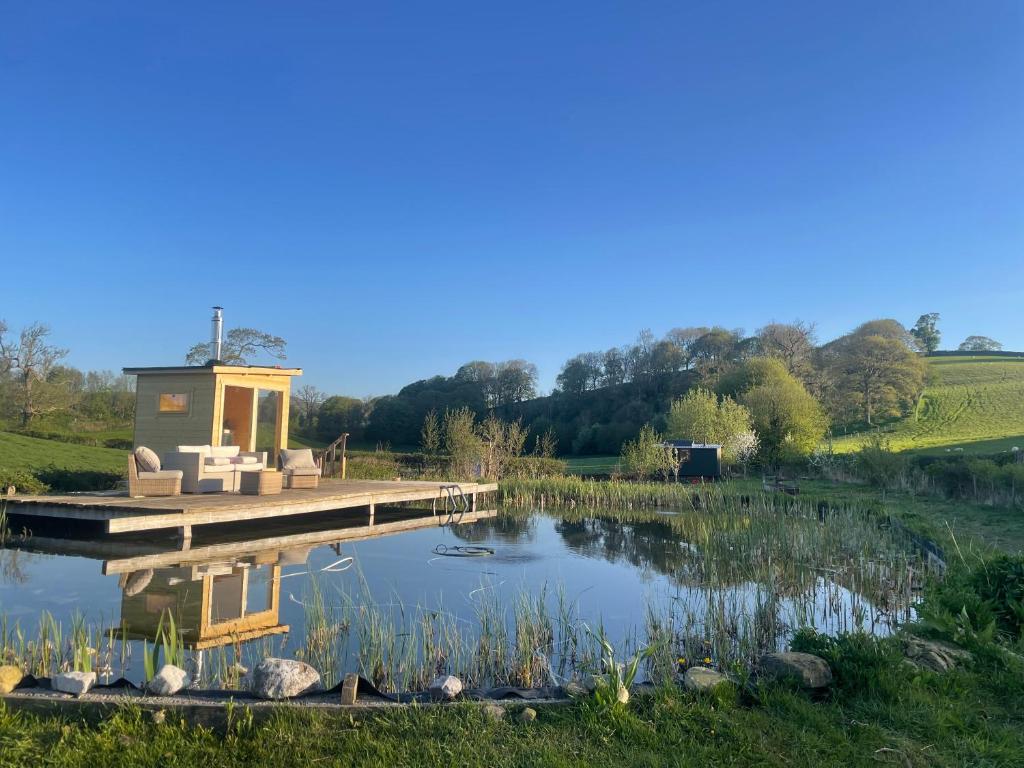 a small building on a dock over a lake at "The Studio" Contemporary studio with organic swimming pool in Skelsmergh
