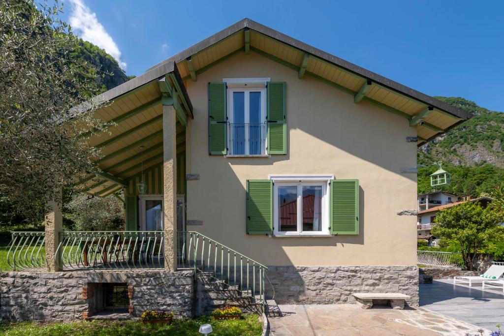 a house with green shutters and a porch at La dolce riva - lake Cottage in Onno