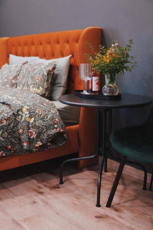 a table with a vase of flowers and a bed at Riverside weekend cabin in Upesciems