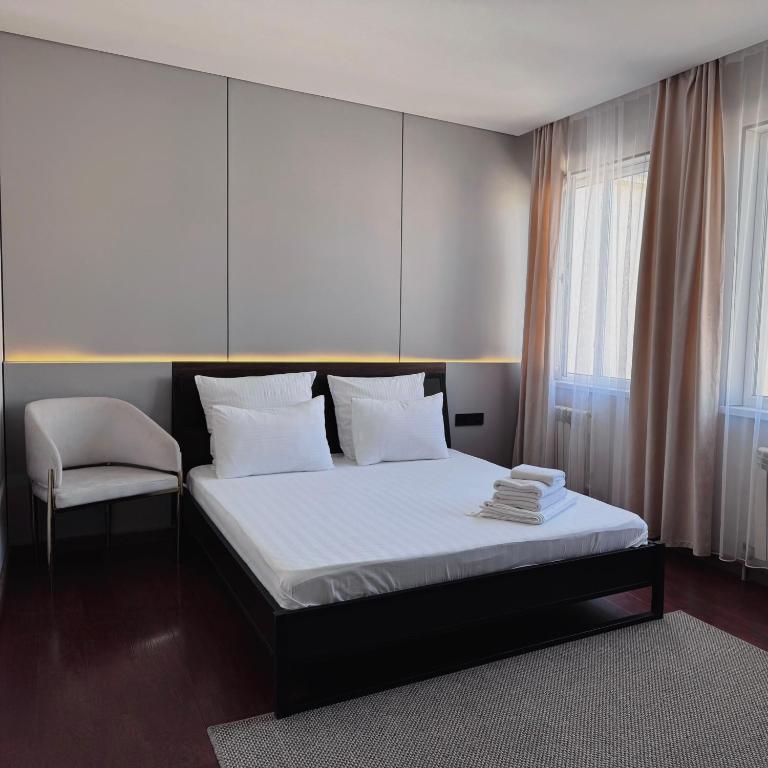 a bedroom with a large bed and a chair at Hotel Mansuri in Almaty