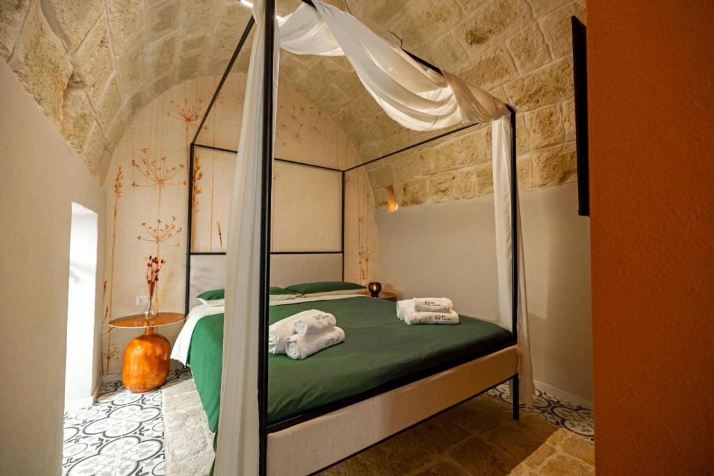 a bedroom with a canopy bed with green sheets at Aria d'amare in Mola di Bari
