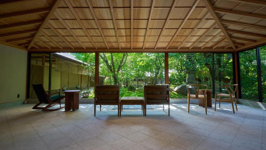 a conservatory with chairs and a table and some windows at Yakakutei in Kirishima
