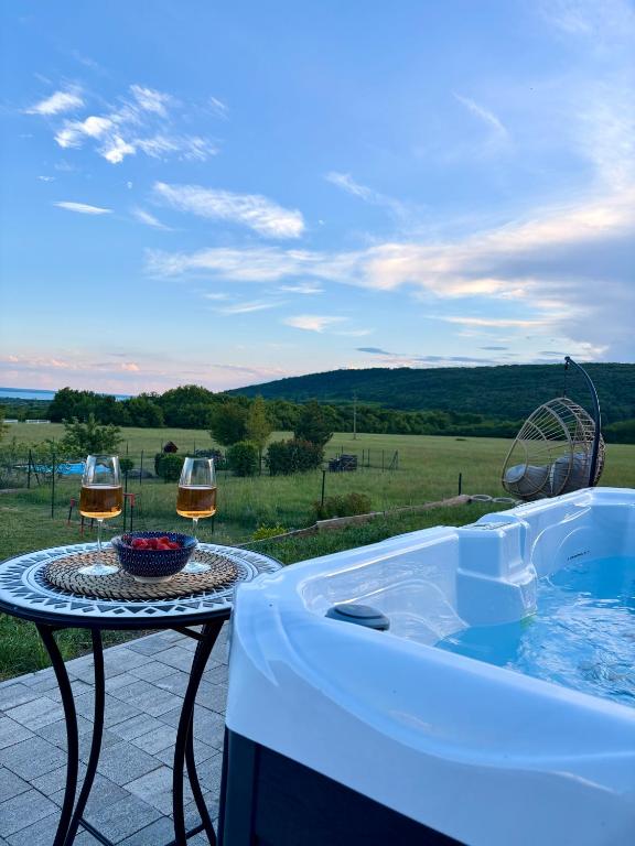 a hot tub sitting on a patio with two glasses of wine at Pannon Grace Balaton in Dörgicse