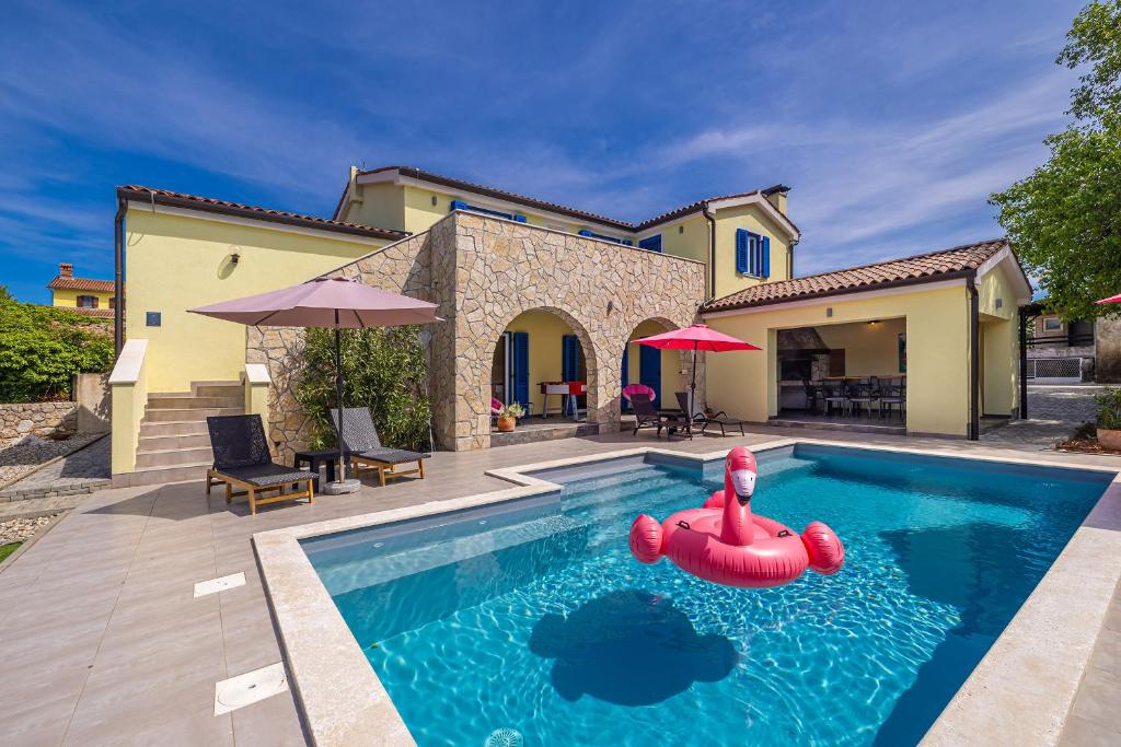 a swimming pool with an inflatable raft in front of a house at Holiday house MARLY with private pool in Kras