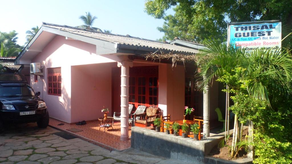 
a white house with a red door and a white couch at Thisal Guest House in Polonnaruwa
