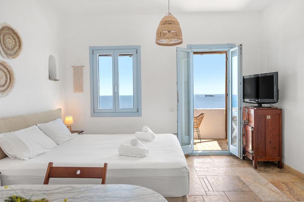 a room with a bed and a tv and a balcony at Sea view rooms in kardiani by TinosStay in Kardhianí