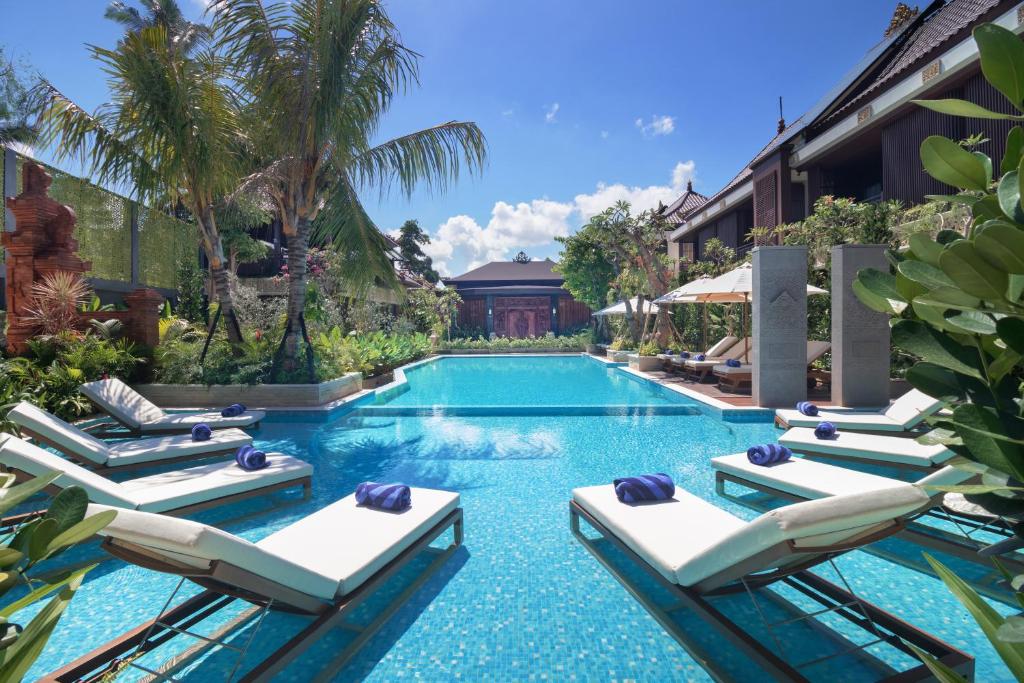a swimming pool with lounge chairs and a resort at MĀUA OLEA Ubud by Swiss-Belhotel in Ubud