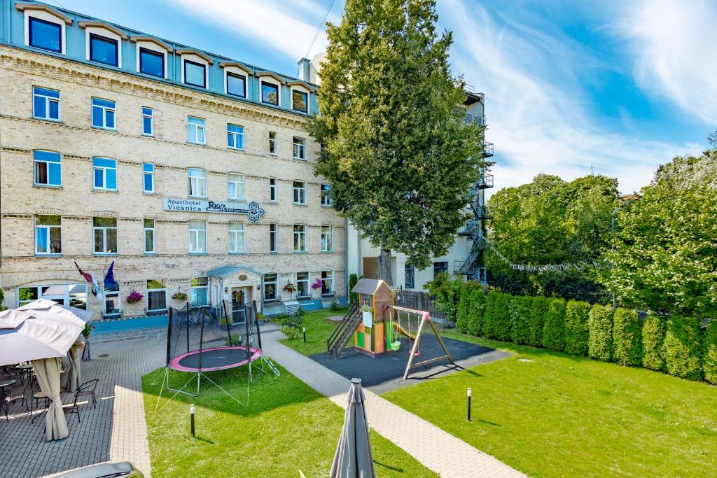 an apartment with a playground in front of a building at RigaApartment SoNaDA Self Check-in Aparthotel, Center, Private Parking in Riga