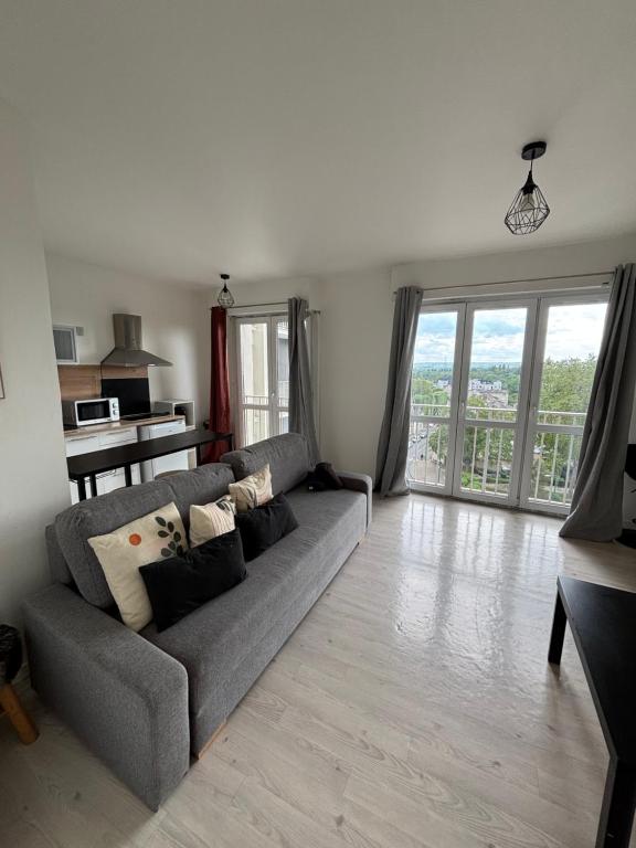a living room with a gray couch and a table at Grand studio lumineux proche gare in Saint-Ouen-lʼAumône