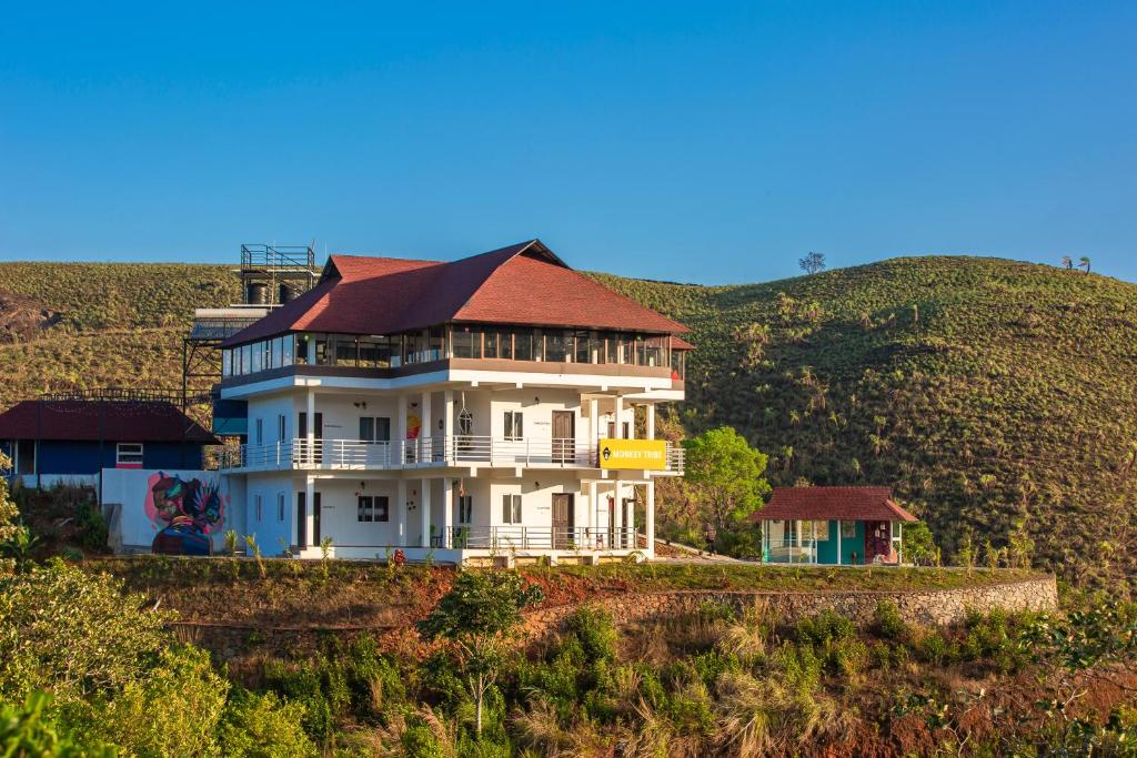 a large white house with a red roof on a hill at Monkey Tribe Vagamon in Vagamon