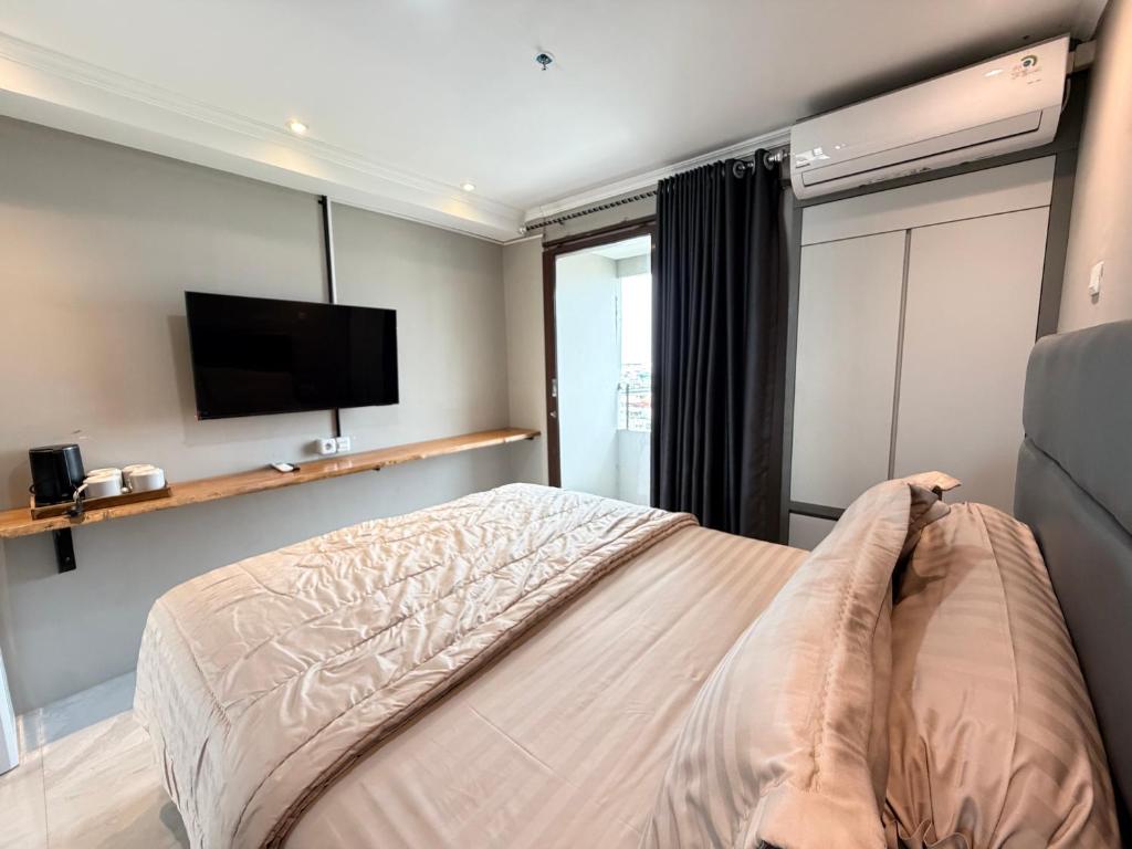 a bedroom with a bed and a flat screen tv at SkyBreeze Sentraland in Medan