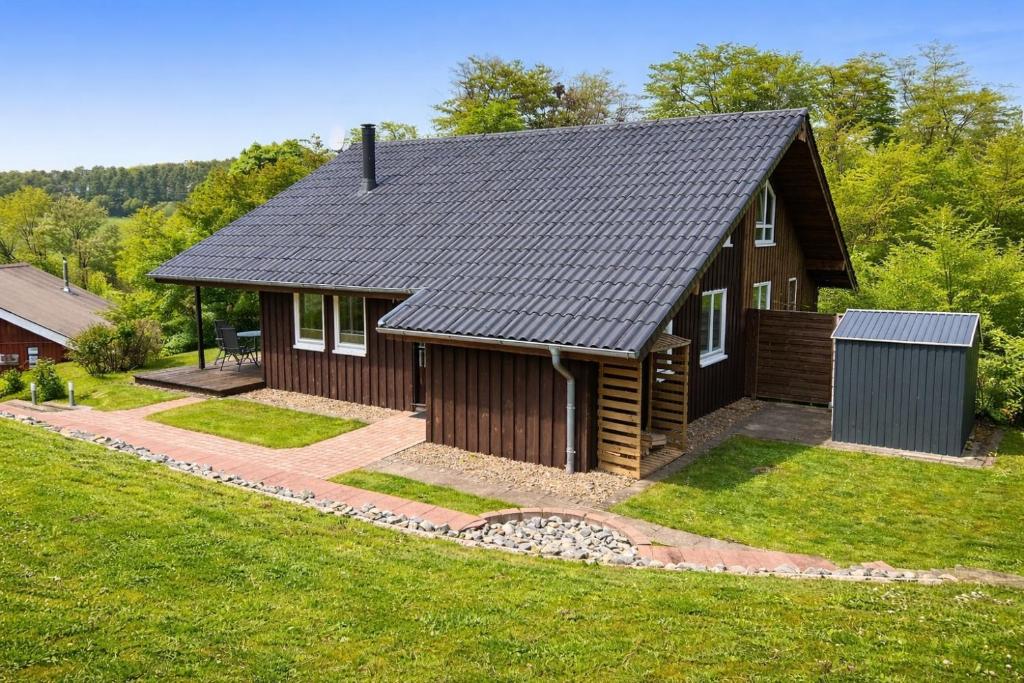 a small house with a black roof on a yard at Extertal-Ferienpark - Sonnenhügel in Extertal