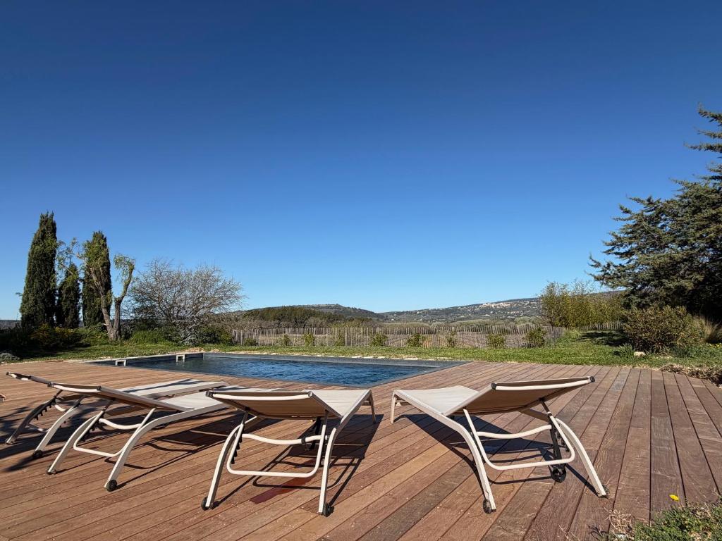a group of chairs sitting on a deck next to a pool at Le Mas Réséda in Goult