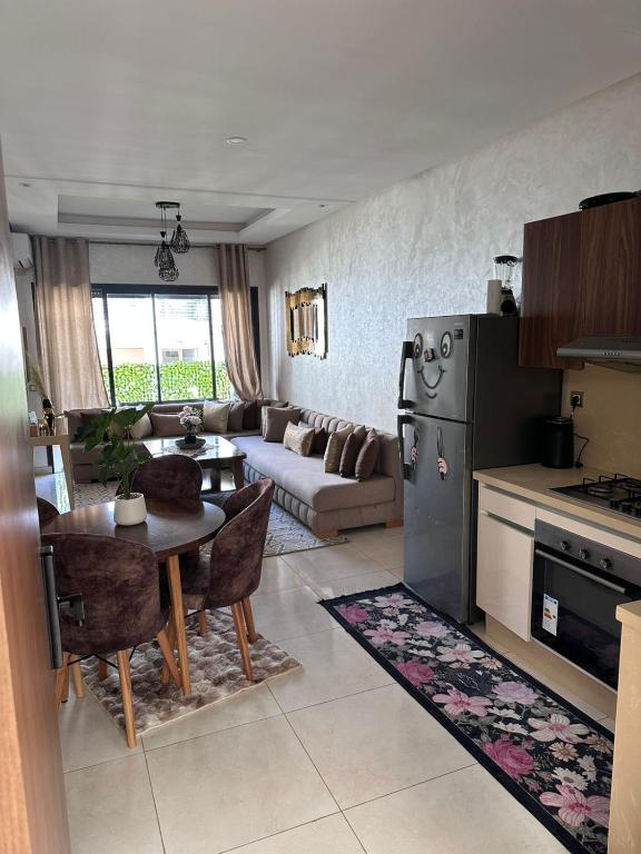 a kitchen and living room with a table and a couch at Studio Luxe Bouznika Beach Piscine, Clim, Wi-Fi ,Check in 24h Plage 5 min in Bouznika