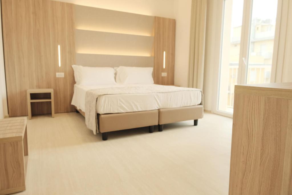 a bedroom with a bed with white sheets and pillows at Hotel Mariblu in Rimini