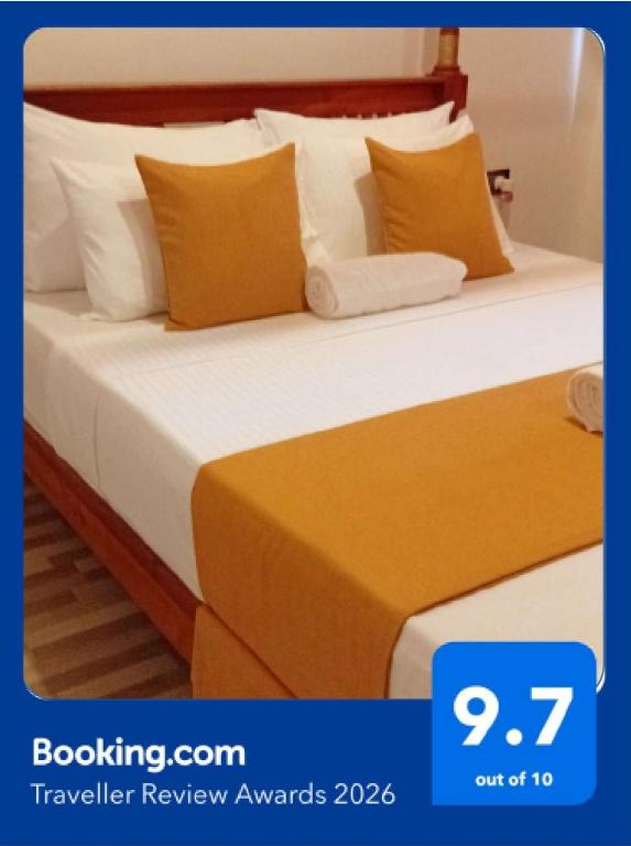 two beds in a hotel room with yellow and white pillows at Holiday Home Ragama in Ragama