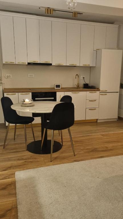 a kitchen with a table and chairs and white cabinets at Scandinavian Studio Bucharest in Dudu