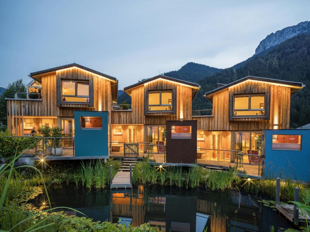 a house on the water with mountains in the background at Bio Chalets Alpegg in Waidring
