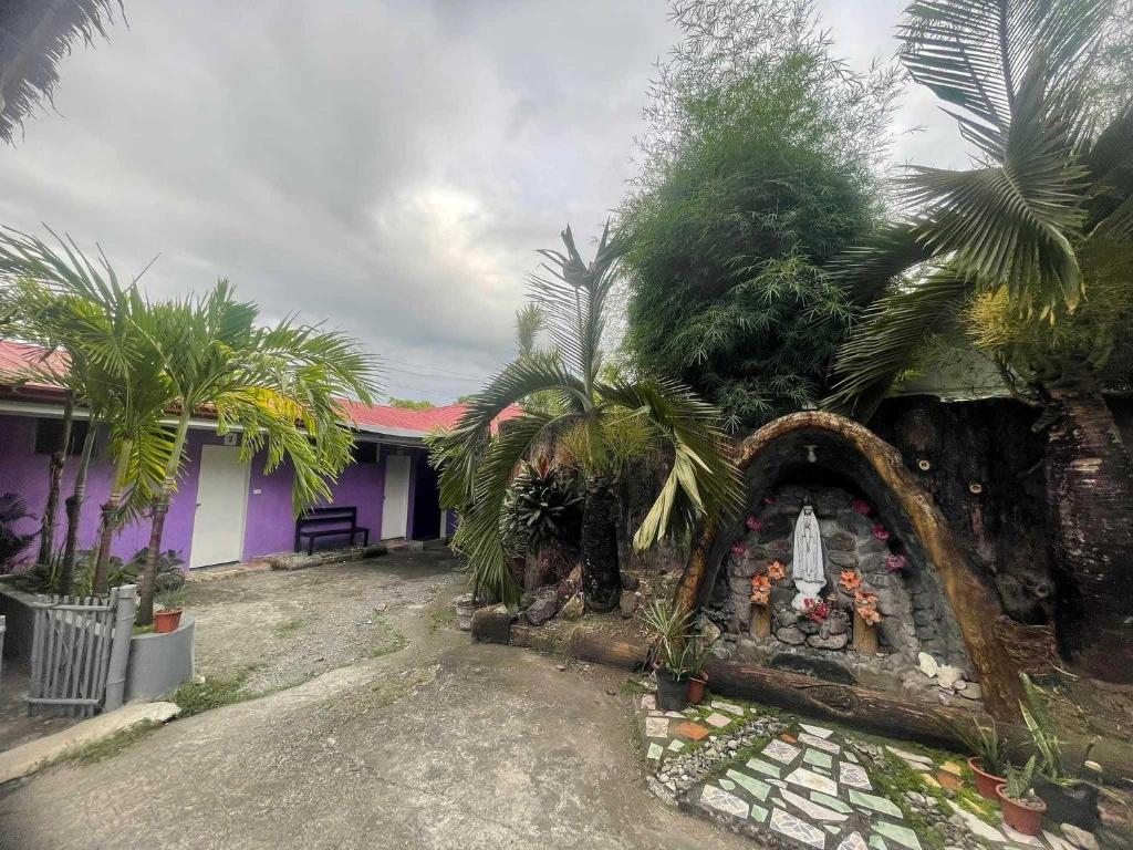 a house with a garden with a stone fireplace at OYO 1214 Cherry Travellers Inn in San Jose de Buenavista