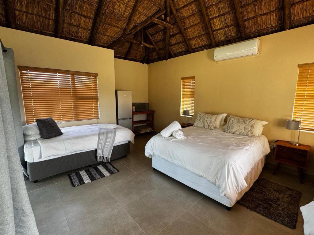 a bedroom with two beds in a room with windows at Halali Wilderness Private Game Ranch in Hammanskraal