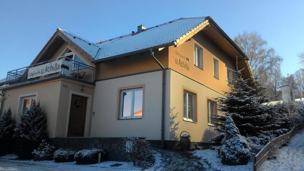 a house in the snow with a tree in front at Achilla Bed & Breakfast in Český Krumlov