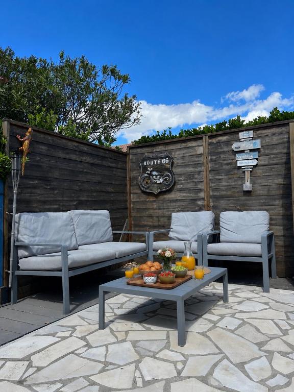 a patio with two chairs and a table with fruit on it at Maison petit havre de paix in Palavas-les-Flots