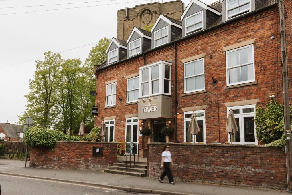 a person walking in front of a brick building at Tower Hotel in Lincoln