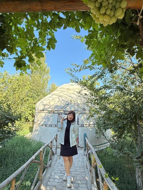 a woman standing on a walkway in front of a tent at Shirin Ethno House Yurt Camp in Shirin