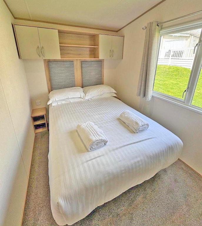 a large white bed in a room with a window at Meadow Lakes in St Austell