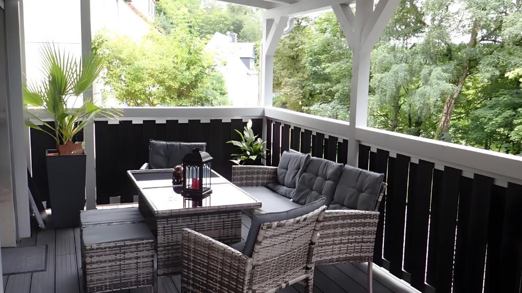 a porch with wicker chairs and a table at Ferienwohnung in Naila in Naila